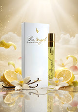 Elegante Produktaufnahme des Parfüms The Angel von Le Flocon. Im Vordergrund steht der goldene 10 ml Flakon neben der weißen Box mit goldener Aufschrift. Umgeben von Zitronenscheiben, Vanilleblüten und schimmernden Lichtpartikeln entsteht eine himmlisch-helle Szenerie, die den frischen, cremig-blumigen Charakter des Duftes symbolisiert.
